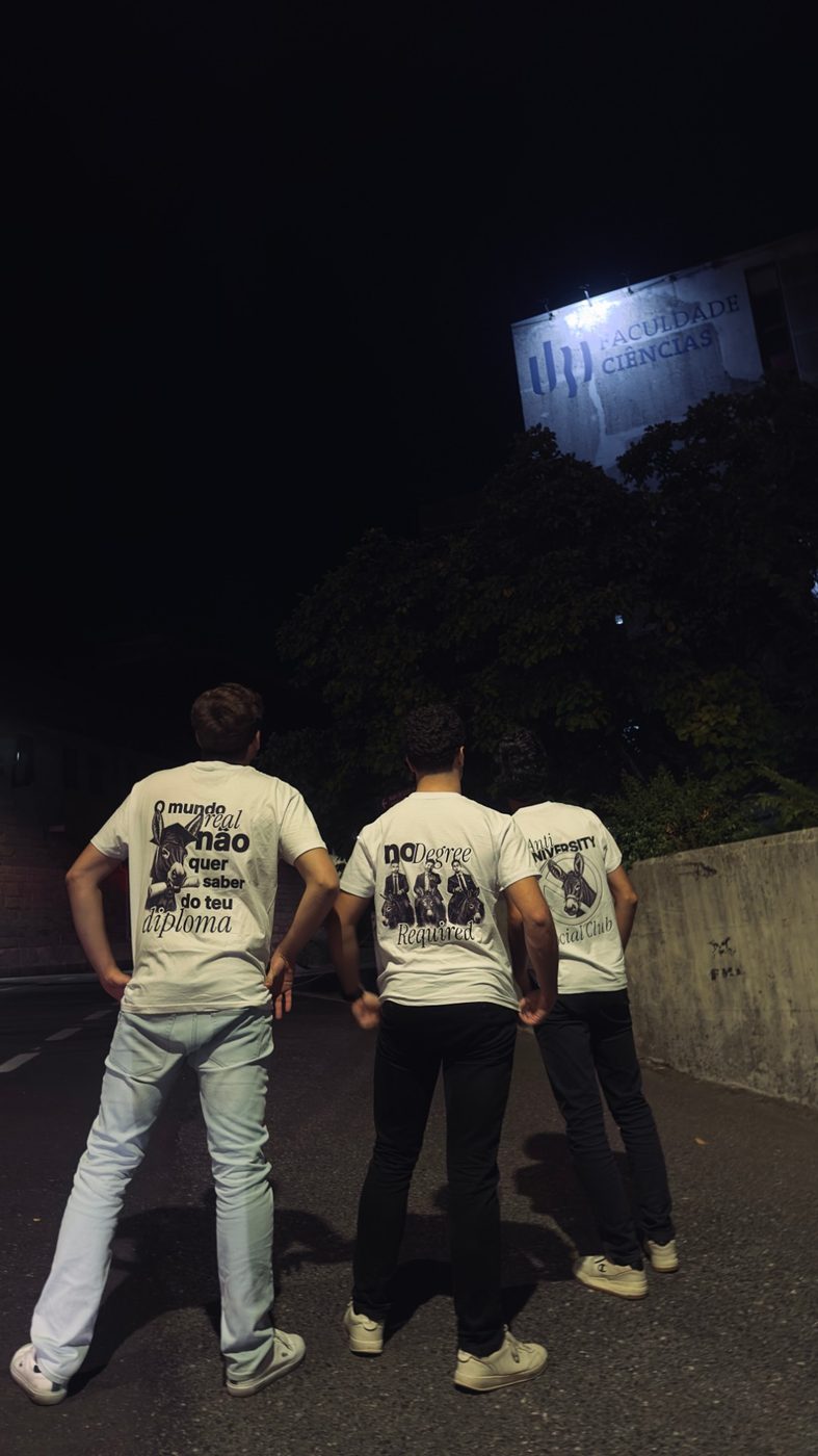 Três pessoas de costas com as t-shirts da coleção Anti University Social Club, à noite, em frente à Faculdade de Ciências